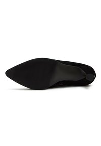 Zapato de tacón alto negro con punta afilada, hecho de ante, con suela texturizada y un diseño elegante, adecuado para ocasiones formales.