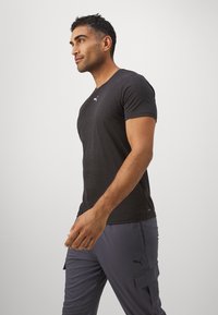 Heren donkergrijze t-shirt met een ronde hals, korte mouwen en een klein wit Puma-logo op de borst, gecombineerd met grijze cargo broek.