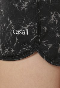 Mustat lyhyet housut, joissa on harmaata marmorikuosia, valmistettu joustavasta kankaasta, ja alareunassa näkyvä valkoinen "casall"-logo.