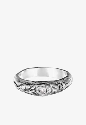 Silberring mit einer strukturierten, unregelmäßigen Oberfläche und einem prominent platzierten klaren Edelstein in der Mitte. Hat ein poliertes Innere.