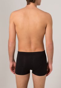 Svarta bomullskalsonger, åtsittande design, slät textur, midjehöjd, utan synliga mönster eller dekorationer, sett bakifrån.