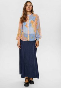 Ljusblå och persikofärgad blus med volang fram, blommönster, lång ärm; kombinerad med en lång mörk denimkjol och svarta platåskor.