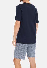 T-shirt en coton bleu marine à manches courtes et coupe décontractée, associée à un short léger bleu clair à motifs avec un design géométrique en losanges.
