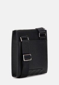 Czarna skórzana torebka na ramię z fakturowaną powierzchnią, srebrnymi okuciami, regulowanym paskiem i eleganckim prostokątnym kształtem.