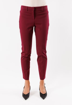 Pantaloni sartoriali borgogna realizzati in materiale liscio, con una vestibilità slim, tasche laterali e una vita di altezza media, abbinati a tacchi neri.