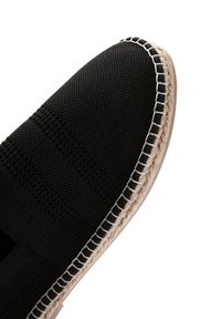 Zwarte textiel espadrille schoen met een geweven jute zool. Voorzien van een gestructureerd bovenwerk en contrasterende witte stiksels langs de rand.