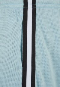 Tissu en mesh bleu clair avec une bordure rayée noire et blanche verticale cousue à la couture centrale.