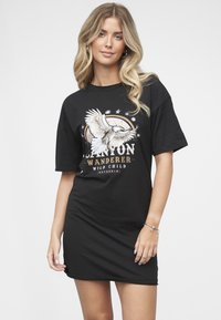 Svart bomulls t-skjortekjole med grafisk design av en ørn, tekst som sier «CANYON WANDERER WILD CHILD», og korte ermer.