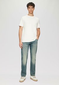 Witte katoenen t-shirt, lichtblauwe denim jeans en witte sneakers met beige accenten. Eenvoudig ontwerp, slim fit en klassieke kleuren.