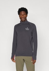 Hosszú ujjú, sötétszürke, állógalléros póló, kontrasztos bíbor árnyalatokkal, mellkason elhelyezett logóval és hüvelyujjnyílásokkal ellátott raglán ujjakkal.