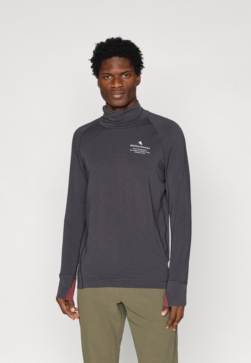 Long-sleeve, dark gray mock neck shirt with contrasting maroon accents, featuring a logo on the chest and raglan sleeves with thumbholes.