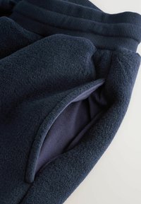 Marineblauwe fleece joggingbroeken hebben een gestructureerde buitenkant, een geribde tailleband en een verborgen zijzak met een zachte voering.