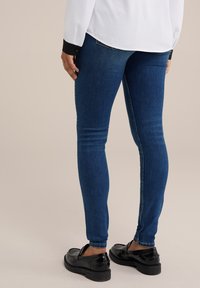 Piegulas džinsi, izgatavoti no denima, ar gludu tekstūru un nelielu stiepšanos. Kombinēti ar melniem loaferiem un baltu garām piedurknēm krekli.