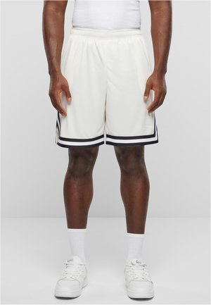 Herenatletiekshorts in licht ivoor met zwarte zijstrepen, elastische tailleband en een relaxed fit. Gecombineerd met witte sokken en sneakers.