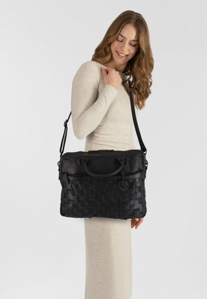 Sac en cuir noir avec une texture tissée, des poignées supérieures et une bandoulière réglable. Il dispose d'une fermeture éclair et d'un accent décoratif en forme d'ancre.