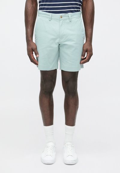 Lichtgroene short van katoen, met een rechte snit, zijzakken en een vlakke voorkant, gecombineerd met witte sneakers en sokken.