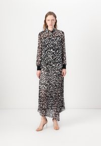 Durchsichtige Blusenkleid mit einem schwarz-braunen Leopardenmuster, langen Ärmeln und einem plissierten Rock. Schwarze Ärmelbündchen und ein Kragen-Detail runden das Design ab.
