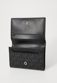 Portefeuille en cuir noir avec un devant à motif gris, fermeture à pression en argent, et plusieurs emplacements pour cartes. Présente un logo en relief et une texture lisse.