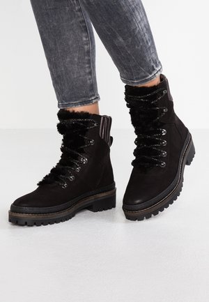 Bottines en suédine noire avec bordure en fausse fourrure, œillets en métal et semelles en caoutchouc épaisses, dotées d'un devant en dentelle texturée.