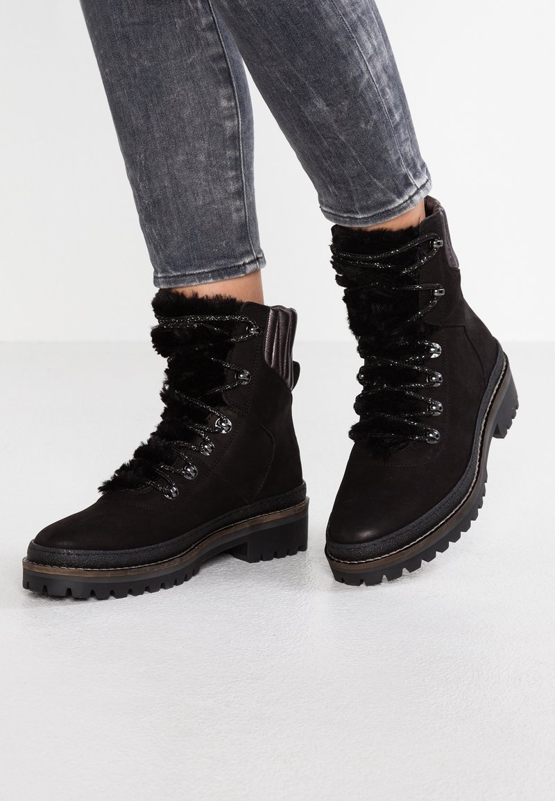 Botas de tobillo de ante negro con ribete de pelo sintético, ojales de metal y suelas de goma gruesas, que presentan un frente con cordones texturizados.