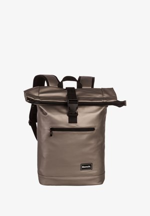 Sac à dos gris à rabat fabriqué en matériau imperméable, avec une poche zippée à l'avant, du matériel noir et des bretelles ajustables pour le confort.