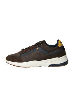Baskets en suède marron avec des accents navy, dotées de perforations sur le bout, d'une semelle intermédiaire blanche et de lacets noirs. Un onglet de talon jaune ajoute un détail.