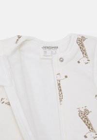 White baby onesie featuring light brown giraffe prints. Made from soft cotton, includes a front snap closure and a tag indicating size and brand.