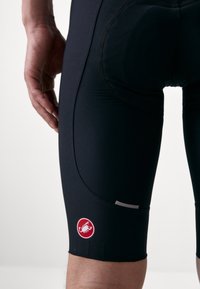 Shorts de cyclisme noirs en tissu extensible, dotés d'un logo rouge contrastant sur le bas de la jambe et de coutures lisses pour le confort.