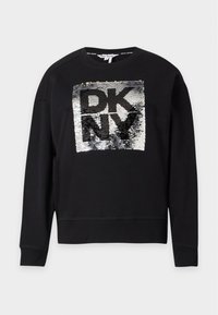 Sweat-shirt noir à manches longues avec un panneau carré en sequins argentés et noirs affichant les lettres DKNY sur le devant.