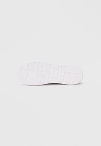 Λευκή σόλα αθλητικού παπουτσιού με υφή και μοτίβο πρόσφυσης, διαθέτοντας λείο εξωτερικό άκρο και ορθογώνιο σχέδιο πέλματος, με ελάχιστη σήμανση στο κέντρο.