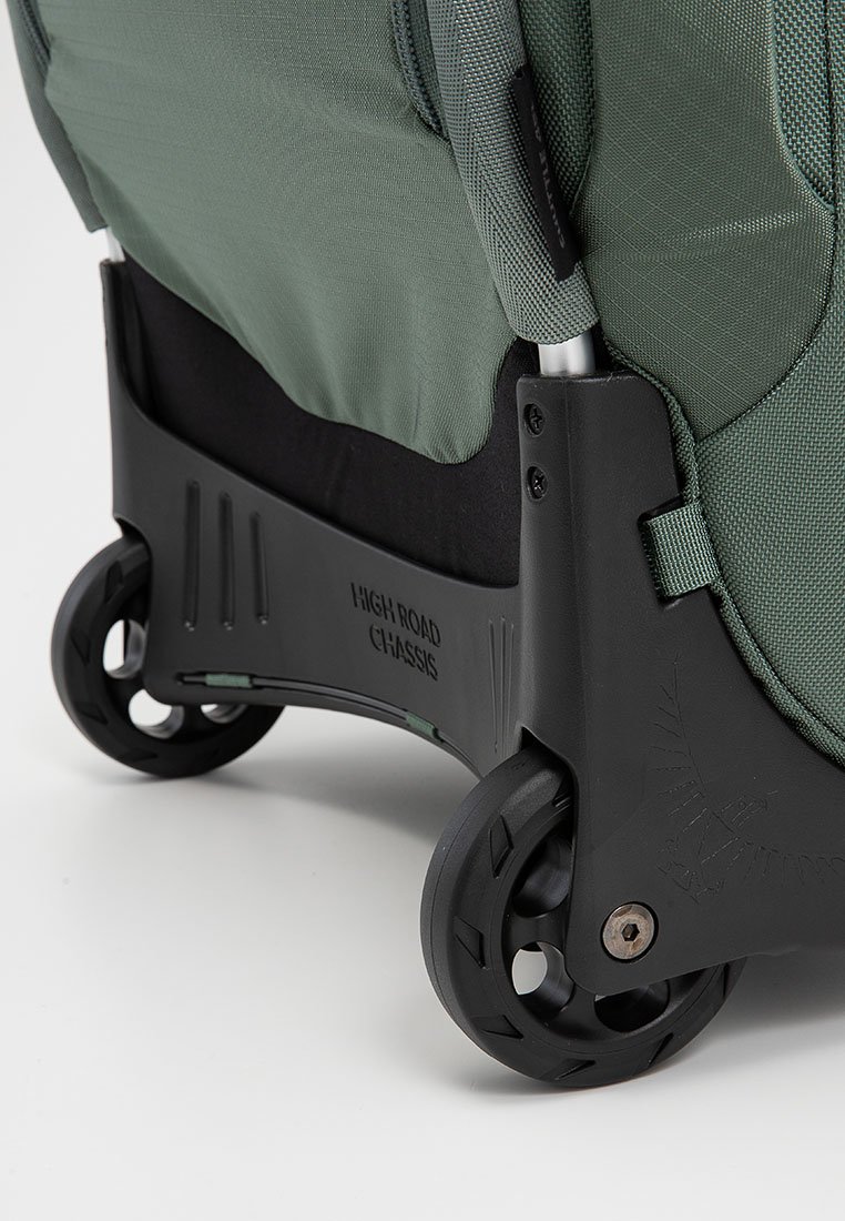 Grüne Reisetasche aus Stoff mit strukturierter Oberfläche, schwarzem Chassis und leichtgängigen Rollen. Verfügt über einen verstärkten Boden für zusätzliche Stabilität.