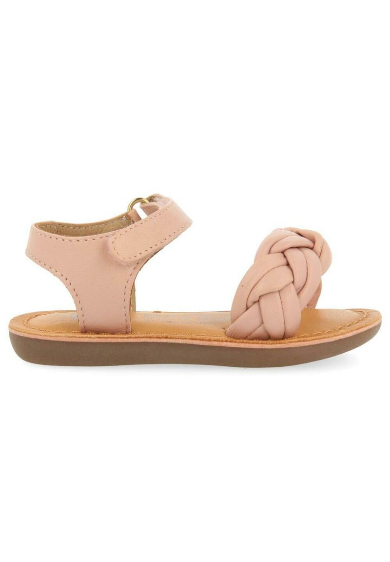 Sandal de cuero rosa claro con un diseño de tira trenzada. Cuenta con una correa ajustable en el tobillo y una suela de goma marrón. Plano y de punta abierta.