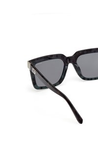 Černé želvovinové sluneční brýle s tmavými skly, ostrým designem a stříbrným akcentem na spáncích. Texturovaný povrch dodává vizuální zajímavost.