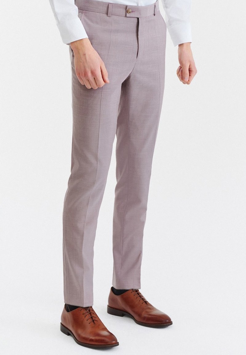 Jasnoszare, dopasowane spodnie o gładkiej fakturze, z wąskim krojem i zapięciem na guzik. W połączeniu z brązowymi skórzanymi butami wizytowymi.