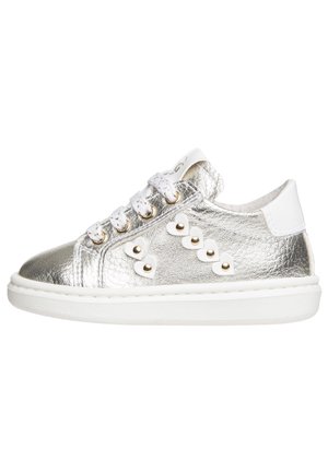 Niski sneaker ze srebrnej metalicznej skóry, białe sznurówki, białe ćwieki w kształcie serca ze złotymi akcentami oraz gruba biała gumowa podeszwa.