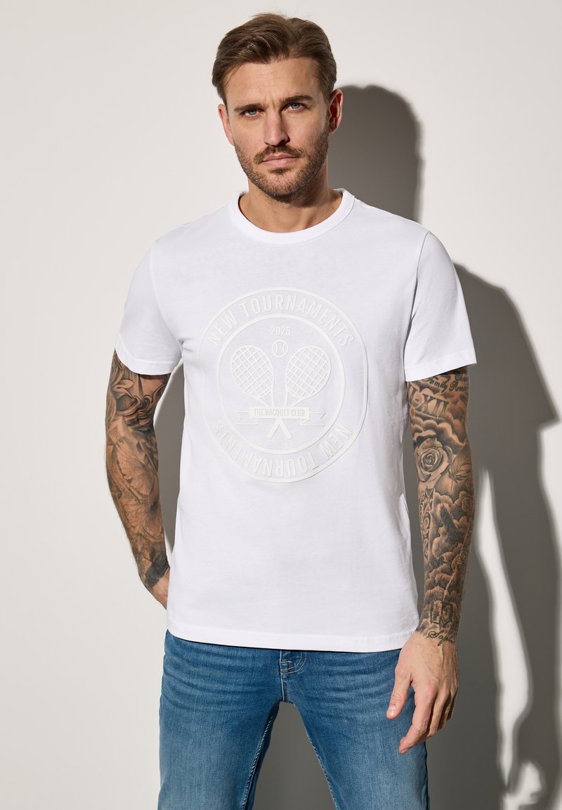 Bílý bavlněný tričko s kulatým logem tenisové rakety v vyvýšeném tisk. Má krátké rukávy, kulatý výstřih a pohodlný střih.