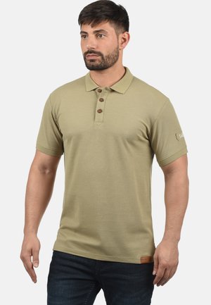 Polo majica kratkih rukava u svijetloj maslinastoj boji, s tri gumba na kopčanju, rebrastim ovratnikom i teksturiranim materijalom, s oznakom logotipa na rubu.