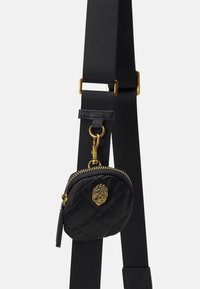 Czarna pikowana mini torebka z złotymi elementami i detalem zamka błyskawicznego, przymocowana do czarnego regulowanego paska. Miękka faktura tkaniny.