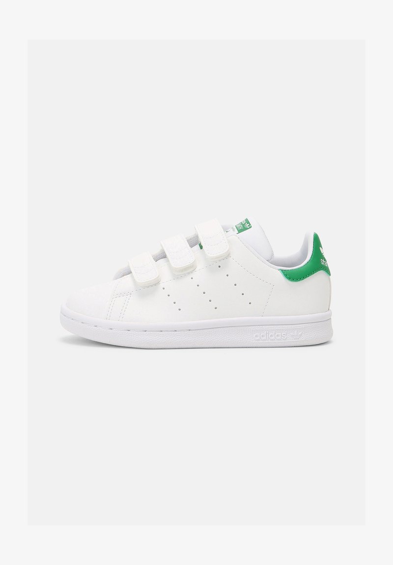 White sneaker with green accent on heel, made of synthetic material. Features three Velcro straps and perforated sides for breathability.