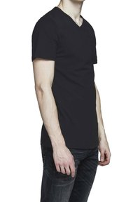 T-shirt nera a scollo a V con maniche corte, realizzata in tessuto solido, caratterizzata da un design slim fit, indossata con jeans in denim scuro.
