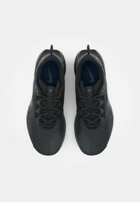 Czarne buty sportowe z fakturowaną cholewką i siateczkowymi akcentami. Posiadają ciemnoniebieską wkładkę oraz kontrastujące szare podeszwy. Sznurowadła i logo w kolorze czarnym.