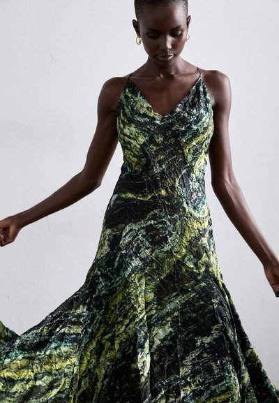 Vestido de estampado verde y negro con escote en V y tirantes finos, que presenta una silueta fluida y tela texturizada.