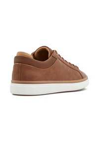 Zapatilla de cuero marrón con acabado texturizado, suela de goma blanca y acentos en marrón claro en el talón y la lengüeta; cuenta con cordones redondos.