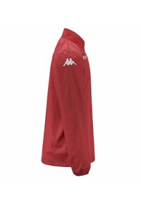 Giacca rossa realizzata in tessuto leggero, con colletto alto, maniche lunghe e un logo bianco sulla spalla sinistra.