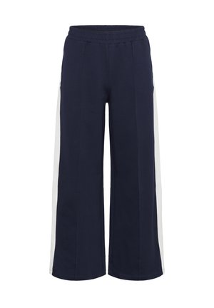 Pantalons de jogging bleu marine avec taille élastique, présentant des panneaux latéraux blancs et un design ample à jambes larges dans un tissu doux.