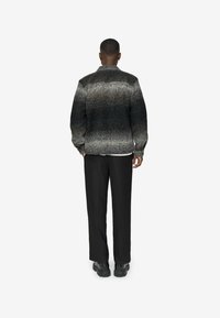 Chaqueta de lana gris ombré con cuello alto, mangas largas y tejido texturizado, combinada con pantalones negros y zapatos negros resistentes.