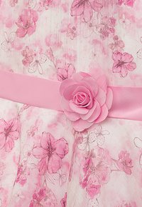 Rosa geblümtes Kleid mit einer strukturierten Stoffoberfläche und zarten Blumenmotiven. Verziert mit einem rosa Satinband und einem dreidimensionalen Blumen-Detail.
