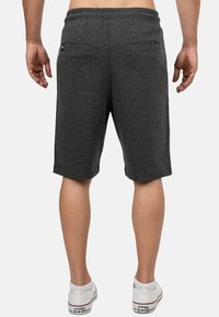 Donkergrijze katoenen shorts met een comfortabele elastische tailleband, twee achterzakken en een iets losse pasvorm, gecombineerd met witte schoenen.
