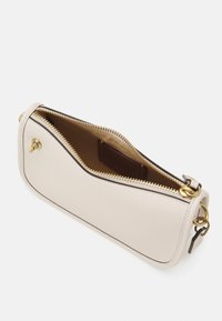 Sac en cuir beige clair avec un design incurvé. Équipé d'une fermeture éclair et de quincaillerie dorées. L'intérieur est doublé de tissu marron, avec un emplacement pour cartes.