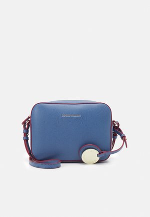 Niebieska teksturowana prostokątna torba na ramię z czerwonym obszyciem, regulowanym paskiem, małym okrągłym przypiętym breloczkiem i subtelnym metalicznym logo marki.